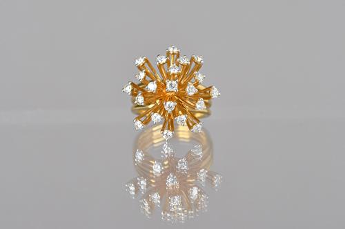 A gold and diamond set ring, in an abstract starburst shaped design, detailed 750 18 K, ring size N, gross weight 12.6 gms, with a case. Illustrated.