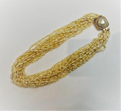 A fourteen row necklace of freshwater Baroque cultured pearls, on a gold and mabe pearl clasp, with ridged decoration, detailed 14K 585, with a pouch