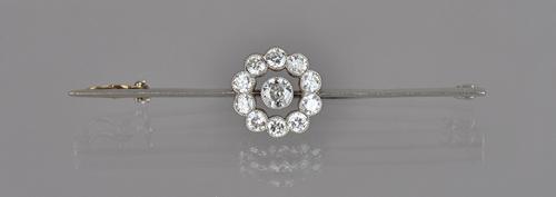 A diamond set cluster bar brooch, collet set with the principal cushion shaped diamond to the centre, in an openwork surround mounted with ten smaller
