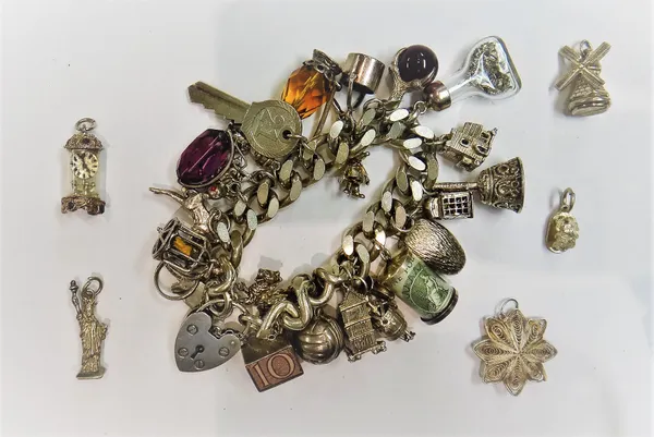 A silver faceted curb link charm bracelet, fitted with a variety of mostly silver charms, on a silver heart shaped padlock clasp and five further loos