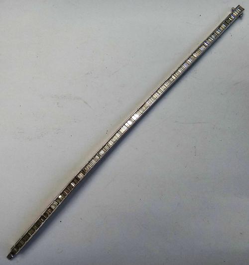 An 18ct white gold and diamond bracelet, formed as a row of baguette diamonds, (the foldover part of the clasp detached, but present), length 17.7cm,