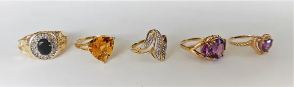 A gold and amethyst three stone ring, claw set with a row of oval cut amethysts, detailed 10 K, a gold and citrine single stone ring, claw set with a