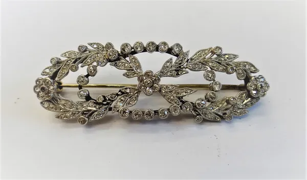A diamond brooch, in a floral, foliate and openwork elongated wreath design, mounted with small cushion shaped and rose cut diamonds.