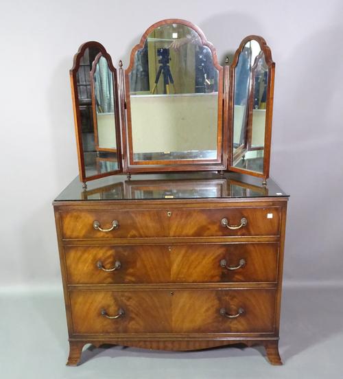 A modern mahogany chest of three long graduated drawers, 92cm wide x 74cm high and an arch top triptych mirror, 49cm wide x 64cm high, (2).   C7