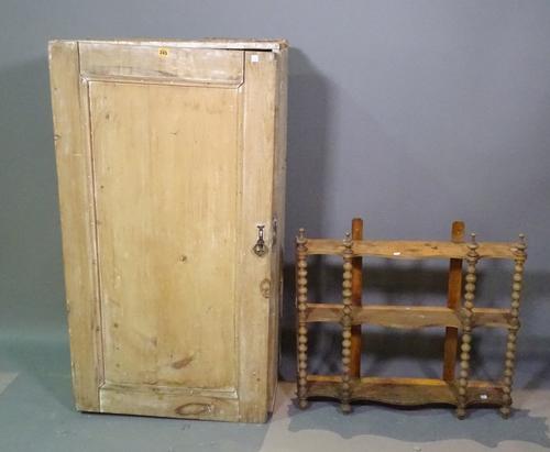 An early 20th century pine cupboard with panelled door, 64cm wide x 118cm high, and an early 20th century stained pine three tier hanging wall shelf w