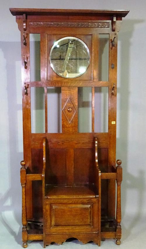 A 19th century oak hall stand with circular mirror and lift top seat flanked by stick stands. 89cm wide, 200cm tall.  M4