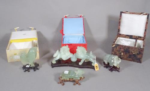 A Chinese green hardstone group, 20th century, carved as two Buddhist lions standing, each with one paw resting on a ball, 22.5cm. length, wood stand