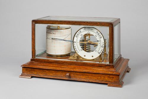 An Edwardian oak cased barographBy Short & Mason, LondonThe rectangular case with bevelled glass panels, fitted with a drawer, on stepped feet, the la