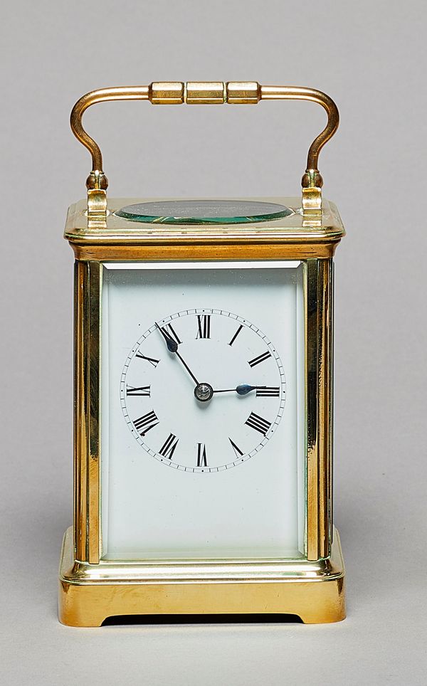 A French brass carriage clock, circa 1900In a corniche case, with an oval glass top above glazed bevelled front, back and sides, with white enamel dia