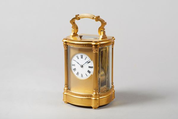 A French gilt brass oval repeating carriage clockCirca 1900In an Anglaise Riche style case, with shaped and fluted handle, above an oval bevelled glas
