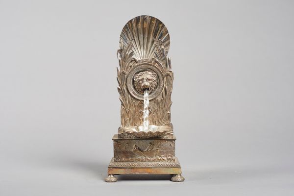 A silvered brass automata watch standIn the Empire styleModelled with a scallop shell above bullrushes, centred by a lion mask 'fountain' head, with s