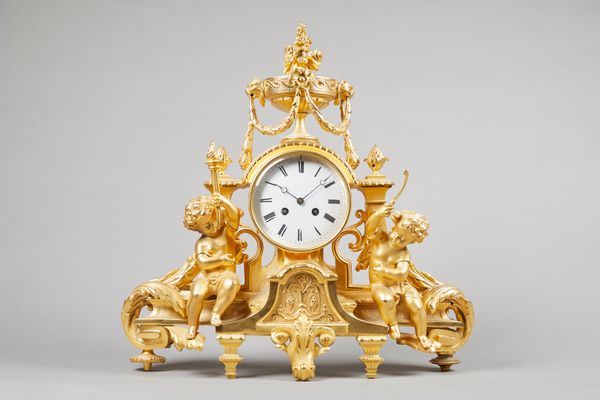 A French giltmetal mantel clockCirca 1860Surmounted by an urn with floral finial and laurel festoons, above a drum-shaped case, flanked to each side b