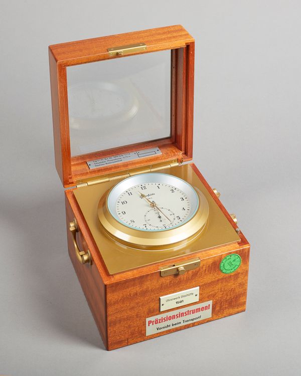 A German quartz battery-operated chronometerBy Uhrenwerk, Glashütte, N0. 1591With a two-tier mahogany case with a glazed lid, with brass bezel, white