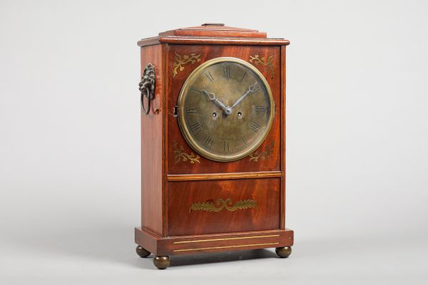 A late Regency mahogany and brass-inalid mantel clockThe case with a chamfered pediment, above a convex glazed glass to the dial, with brass inlay to
