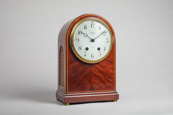 An Edwardian mahogany and boxwood-outlined mantel clockRetailed by Payne & Co. LondonThe arched case with a brass fishscale panel to each side, the fr