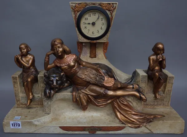 A French Art Deco style ceramic figural mantel clock, titled 'La Favorite', with elevated dial over a recumbent female resting on a lion, flanked by m