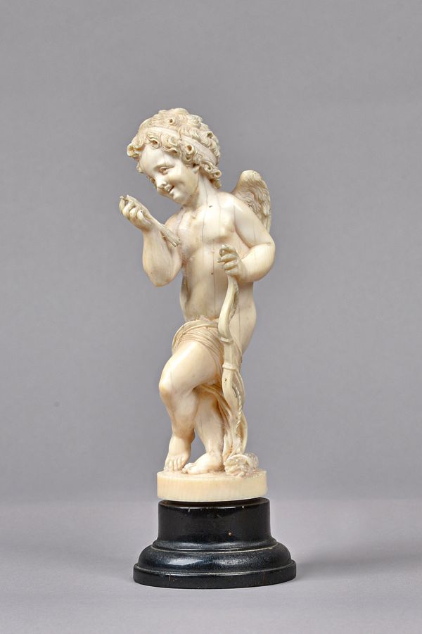 A Dieppe carved ivory 'cupid' figure, early/mid-19th century, raised on an ebonised wooden plinth (figure 16.5cm high) and a 19th century ivory disc w