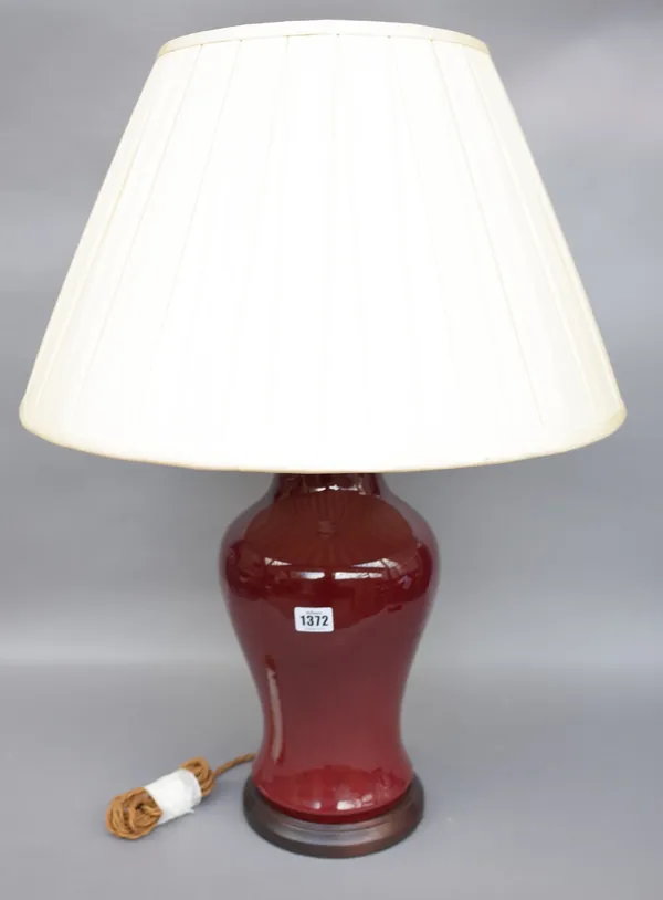 A Chinese porcelain vase table lamp, sang de boeuf, baluster ground with a cream silk pleated shade, vase 40.5cm high.