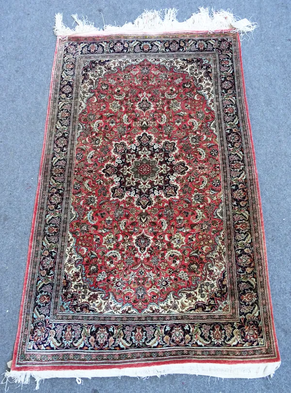 A silk rug, central stylised star medallion within pink red field, allover floral decoration, 160cm x 97cm.