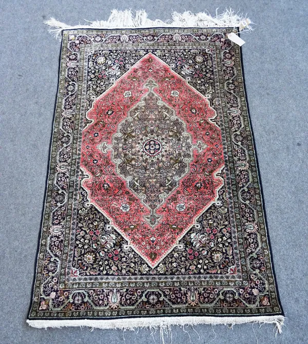 A silk Ghom rug Central Persia, stepped central medallion within pink red stepped field, dark blue black spandrels and main border, 168cm x 110cm.