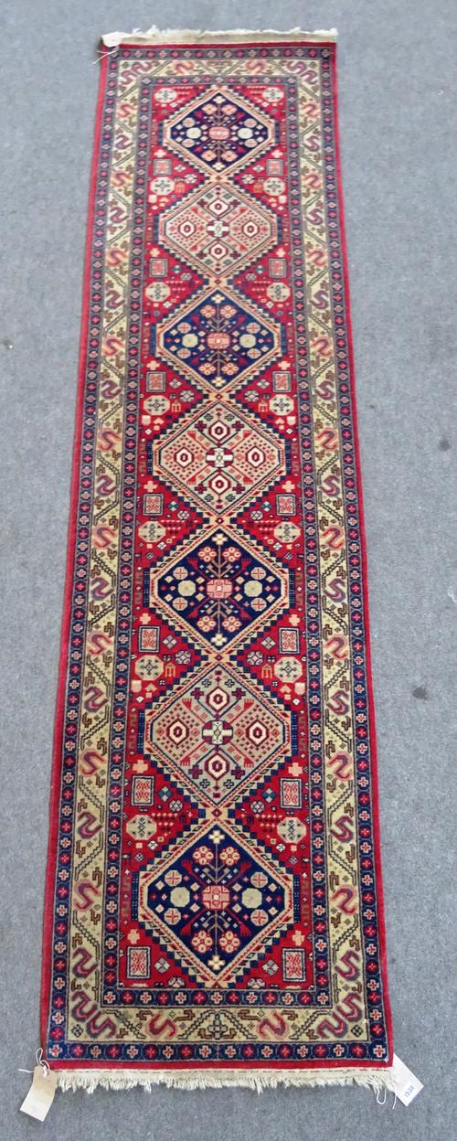A South Persian runner, the madder field with seven diamonds, an ivory border, 295cm x 76cm.