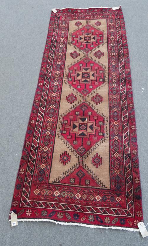 A North West Persian runner, the natural field with three large madder diamonds, a lozenge border, 317cm x 116cm.