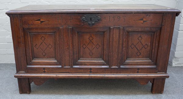 A 16th century oak coffer, the plank top over a triple inlaid front panel dated 1593 on stile feet, 133cm wide x 74cm high x 54cm deep.