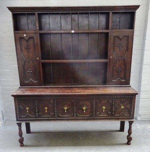 A Charles II style oak dresser, the enclosed three tier plate rack with a pair of cupboards over three geometric moulded drawers on baluster turned co