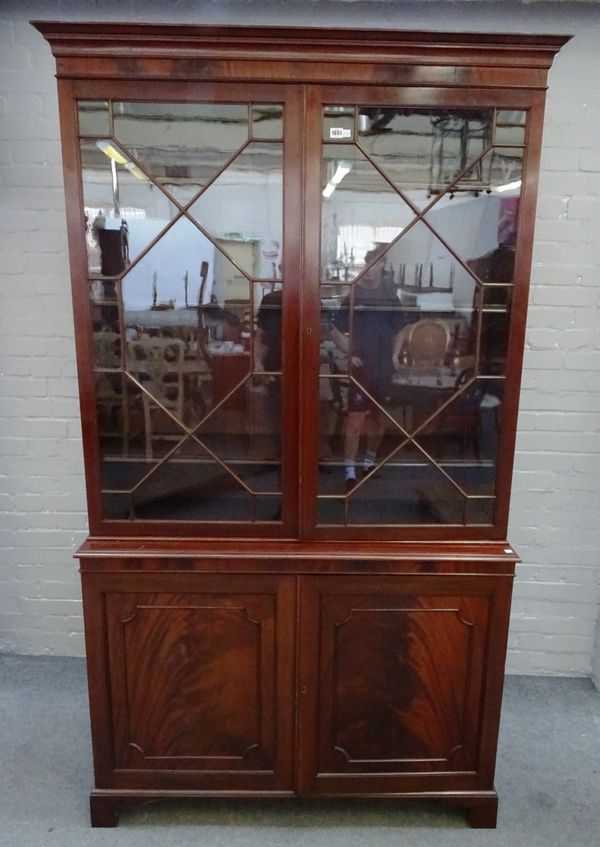 A George III mahogany bookcase cabinet, the pair of astragal glazed doors over a panel lower, on bracket feet, 126cm wide x 220cm high x 39cm deep.