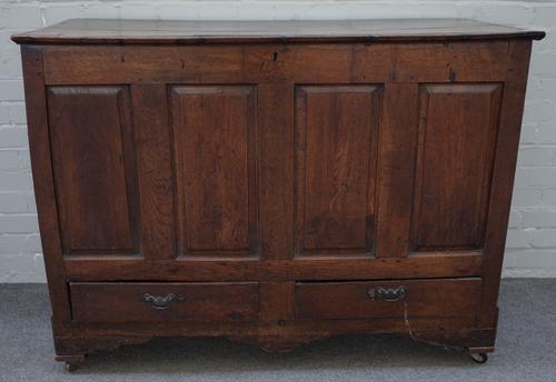 A mid 18th century oak mule chest, the plank top over four panel front and pair of drawers, 125cm wide x 93cm high x 53cm deep.