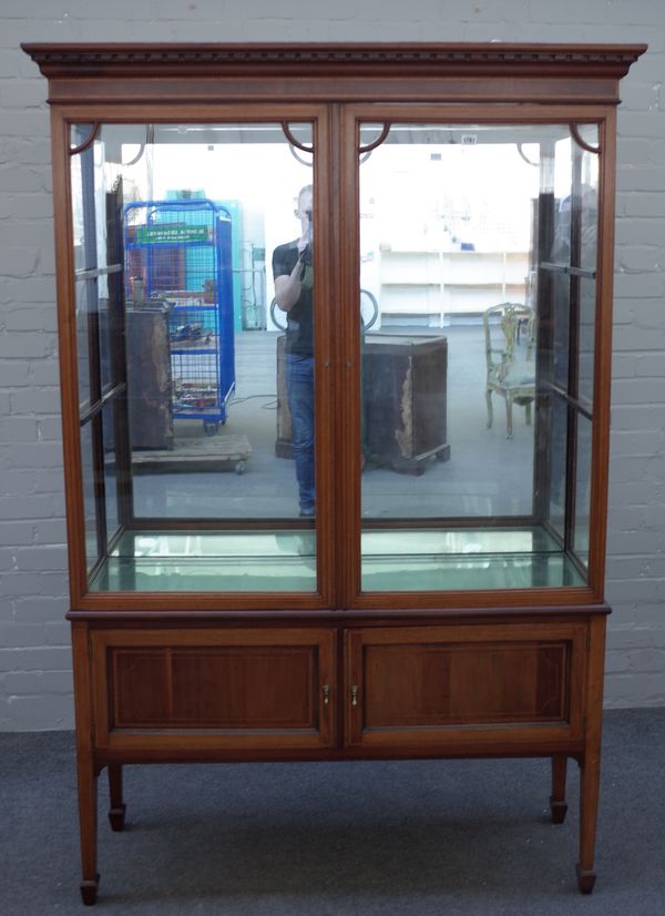 An Edwardian satinwood banded mahogany display cabinet cupboard with pair of glazed doors over a pair of panelled lower doors, on tapering square supp