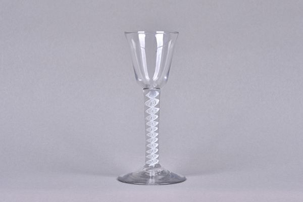 An opaque twist wine glass, circa 1765, the rounded funnel bowl raised on a single-series opaque twist stem and plain foot,15cm.high. Illustrated