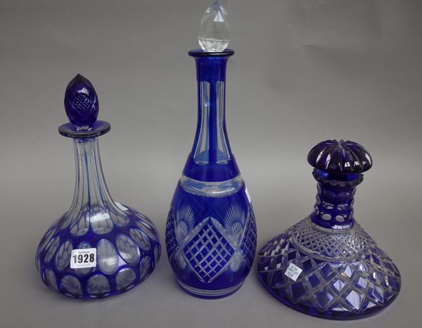 A set of three globe and shaft, hobnail cut decanters, each with lion engraved heraldic crest, a pair of blue flashed cut glass ship's decanters and s