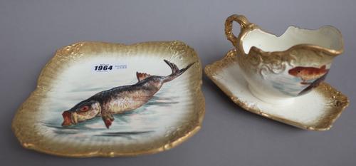 Twenty three German earthenware plates, a large rectangular serving dish and a sauce boat, c. 1900, each transfer printed and overpainted with fish wi
