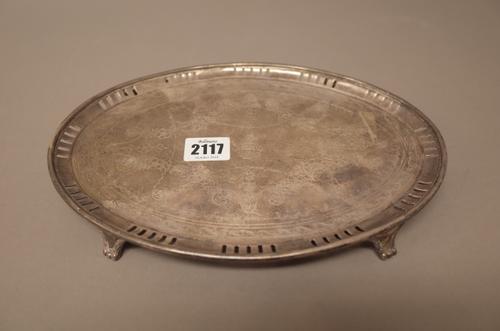A silver oval small salver, the centre later engraved with floral swags within a later pieced border, the centre crest engraved and raised on three fe