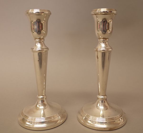 A pair of silver table candlesticks, each raised on a circular base, (loaded), modern, height 18cm.