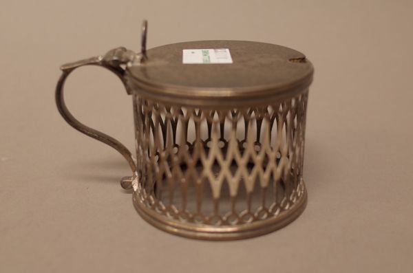 A George III silver mustard pot, of cylindrical form with pierced  decoration, scrolled handle and with a pierced thumbpiece to the plain flat lid, Lo