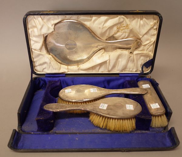 A lady's silver mounted four piece dressing set, comprising; a hand mirror, two hair brushes and a clothes brush, Birmingham 1918 & 1919, with a case.