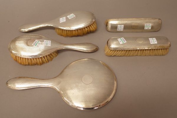 A ladies silver mounted, five piece dressing set, comprising; a hand mirror, two hairbrushes and two clothes brushes, one clothes brush, Birmingham 19