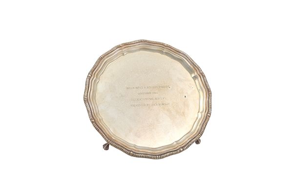 A silver salver of shaped circular form with a decorated rim, raised on four ball and claw feet, the centre presentation inscribed Rolls - Royce & Ben