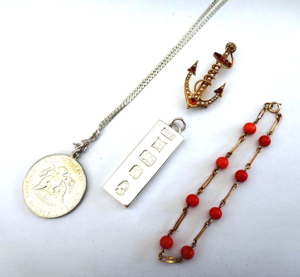 A gold, seed pearl and red gem set brooch, designed as an anchor, a gold and coral bead bracelet, a silver rectangular ingot shaped pendant, a Kennedy