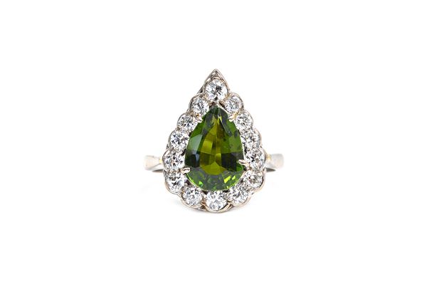 A white gold, green tourmaline and diamond set pear shaped cluster ring, claw set with the pear shaped green tourmaline at the centre in a surround of