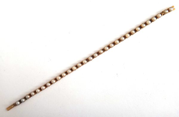 A late Victorian gold and half pearl set bracelet, each flexible link collet set with a half pearl, on a snap clasp, length 14.5cm, gross weight 6.8 g