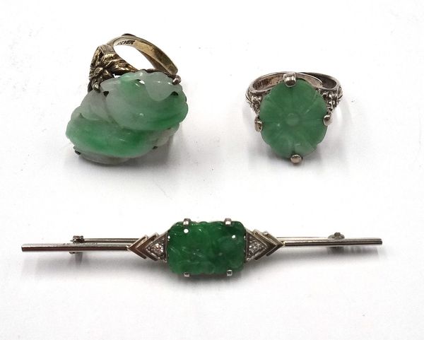 A white gold and platinum, jade and diamond bar brooch, mounted with the rectangular carved and pierced jade to the centre, between two circular cut d