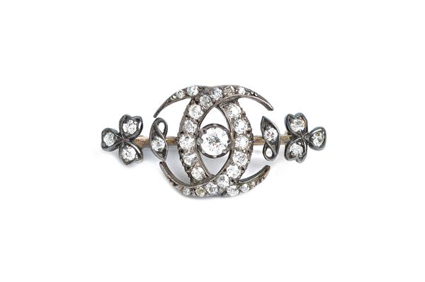 A late Victorian diamond brooch, in a twin crescent and trefoil design, mounted with the principal cushion shaped diamond at the centre and otherwise