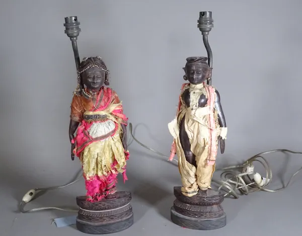 A pair of early 20th century Asian hardwood figural lamp bases, with remnants of costume, 38cm high, (2).   CAB