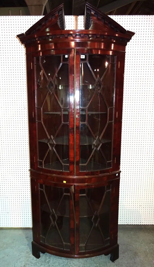 A George II style mahogany bowfront corner display cabinet, 19th century, the broken architectural cornice over two pairs of astragal glazed doors, on