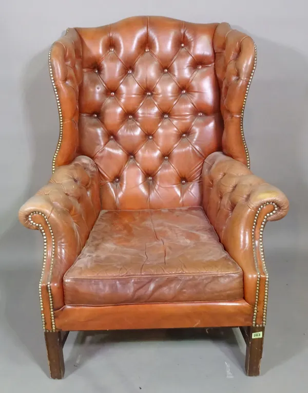 A George III mahogany framed wingback armchair with red button back leather upholstery on block supports.   F7