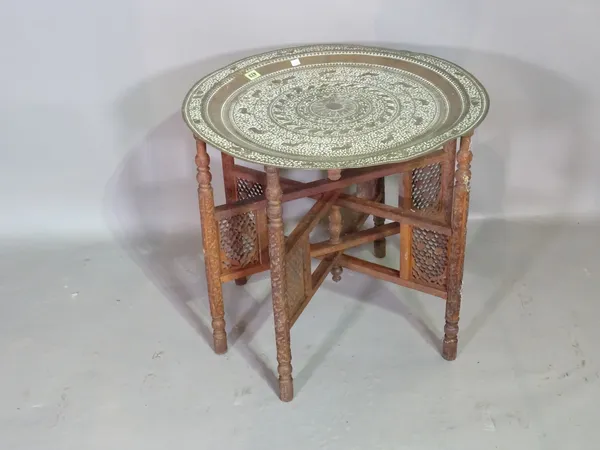 An early 20th century Indian brass embossed table on folding hardwood base, 60cm wide.   G8