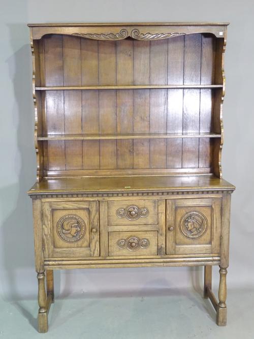 An early 20th century oak dresser with three tier plate rack inset and carved panel doors, 118cm wide x 180cm high. M9